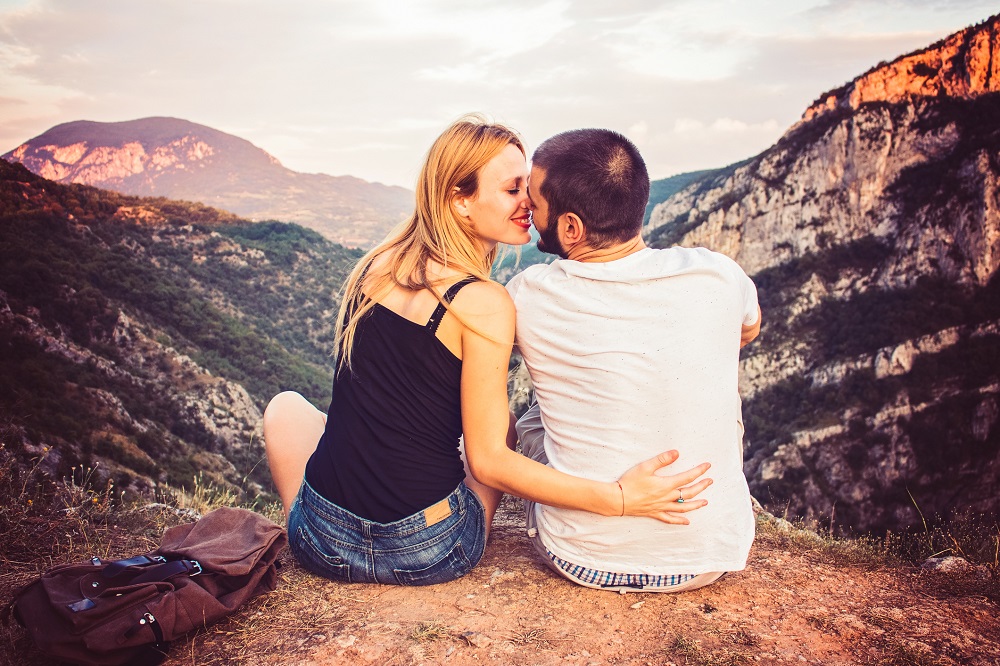Paar küsst sich bei Verlobung vor Bergkulisse