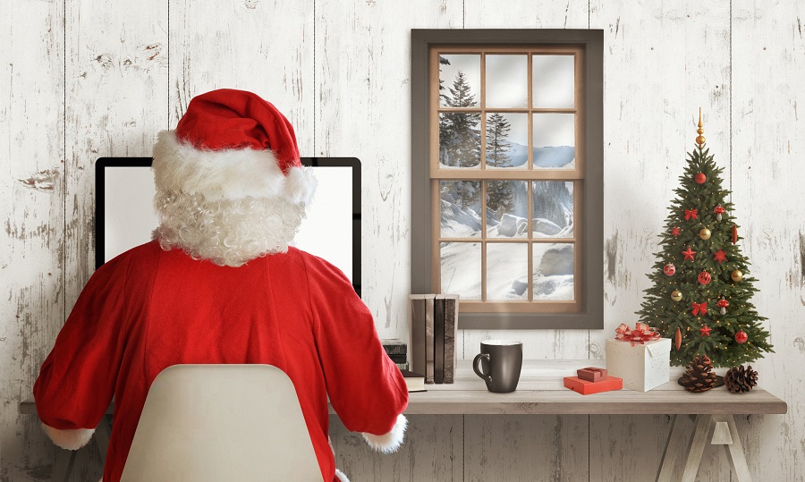 Weihnachtsmann sitzt am Schreibtisch vor dem Computer