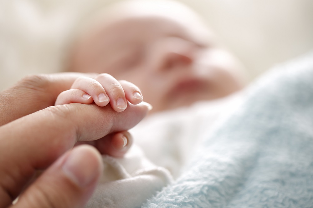 Neugeborenes legt Hand um den Finger der Mutter
