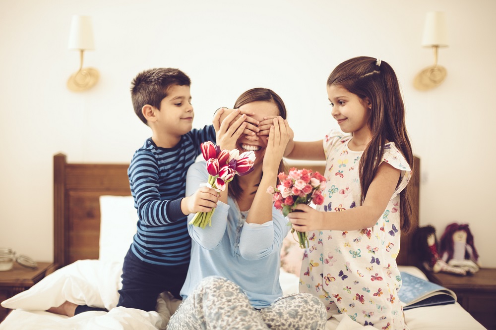 Kinder überraschen ihre Mama mit Blumen.