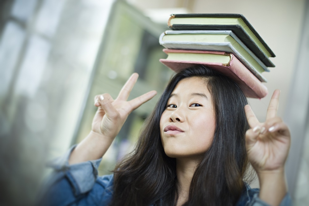  Mädchen balanciert Bücher auf dem Kopf.