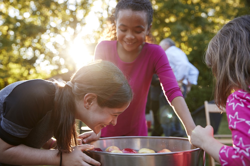 Ältere Kinder spielen Apfel-Schnappen auf dem Kindergeburtstag im Garten