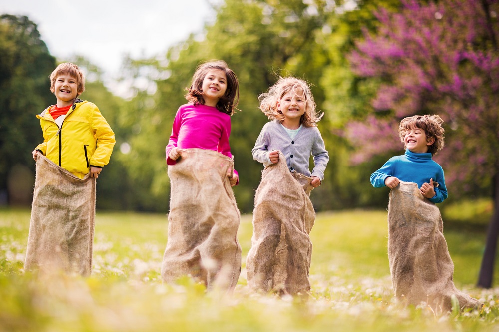 Kinder spielen Sackhüpfen bei Geburtstagsparty im Garten