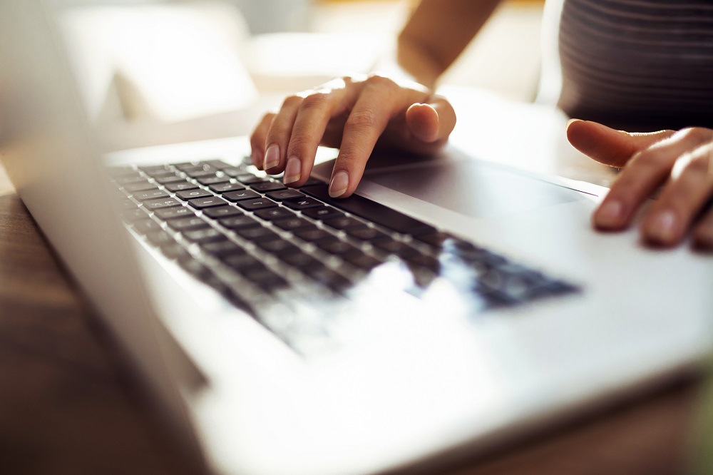 Frau tippt am Laptop einen Brief