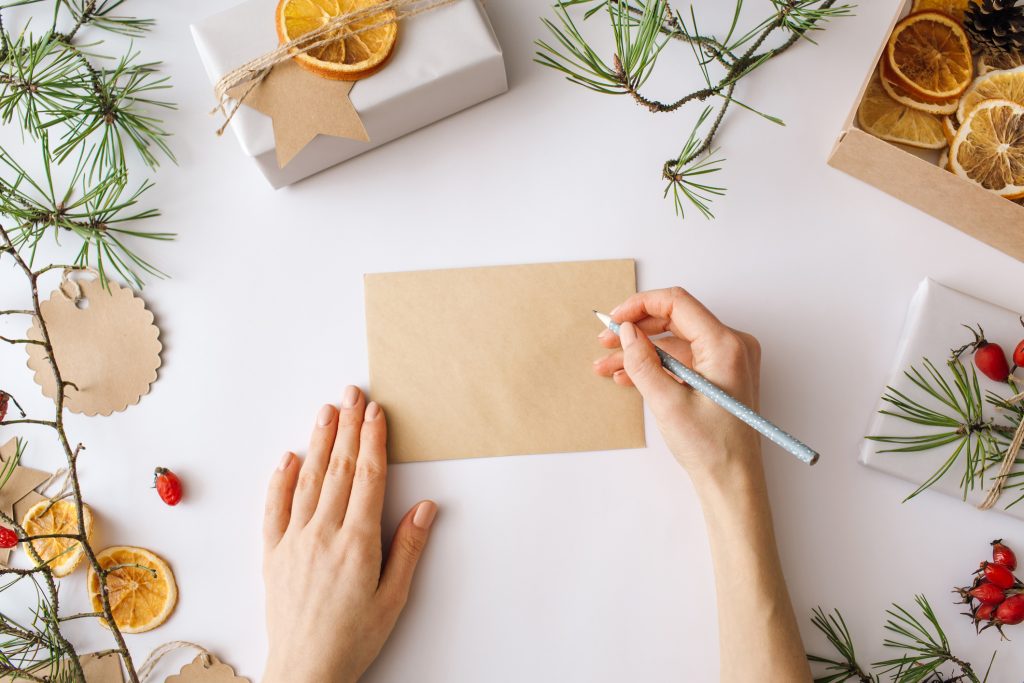 Weihnachtspost schreiben am Tisch mit Geschenken