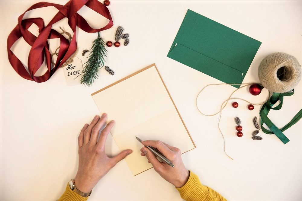 Weihnachtspost schreiben am Tisch mit Geschenken