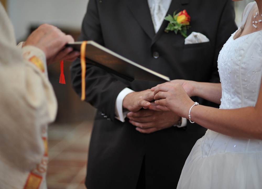 Geistlicher liest das Ehegelübde bei einer Trauung vor