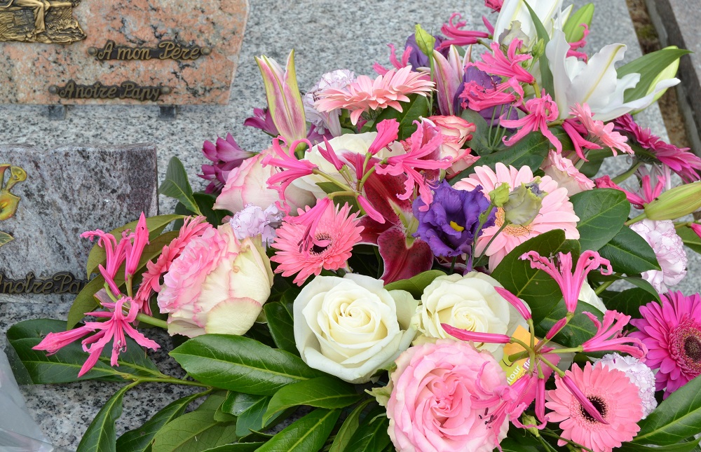 Ein Strauß aus weißen und rosa Blumen vor einem Grabstein