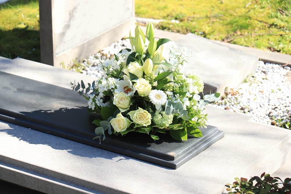 Blumengesteck in Weiß und Creme auf einer Grabplatte