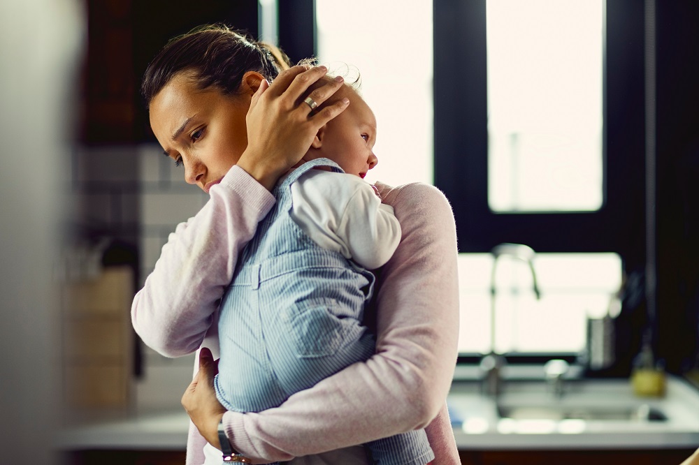 Alleinerziehende Mutter hält Baby auf dem Arm