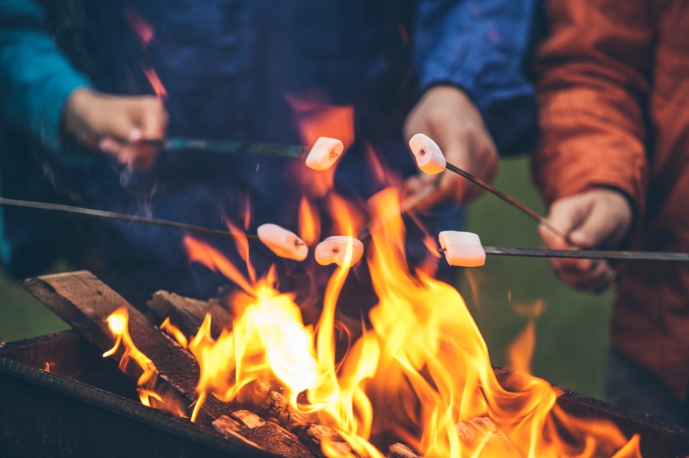 Personen grillen Marshmallows über Lagerfeuer