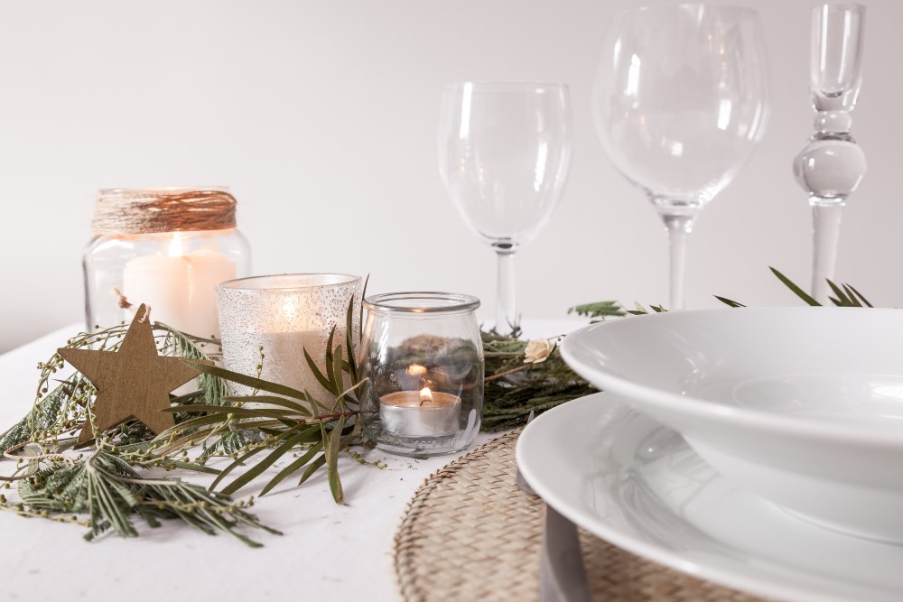weiße Tischdekoration mit Kerzen und Zweigen