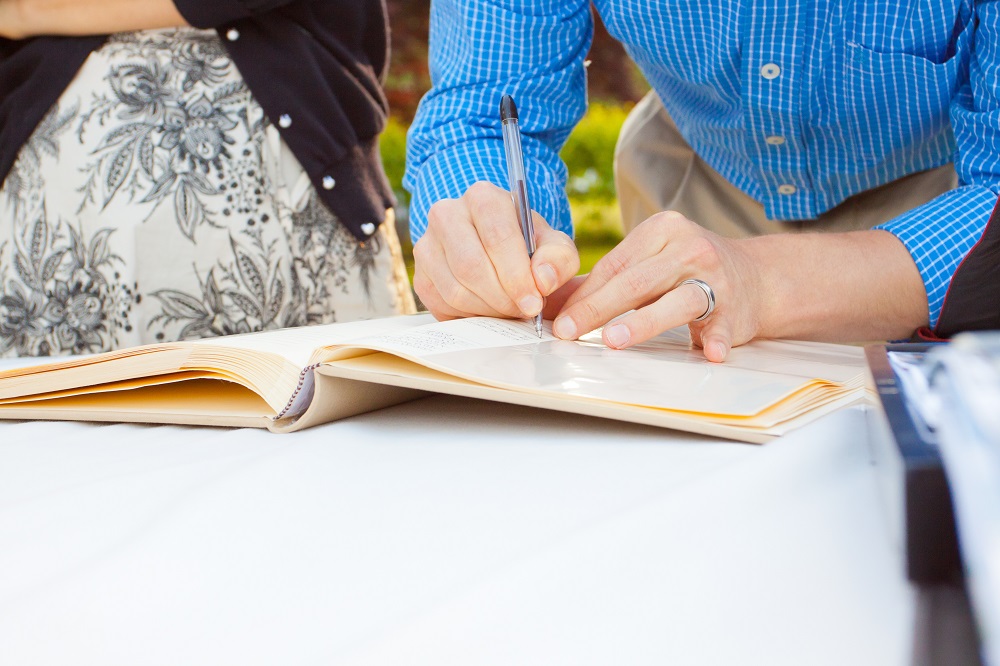 Gäste tragen Glückwünsche zur Silberhochzeit in Gästebuch ein