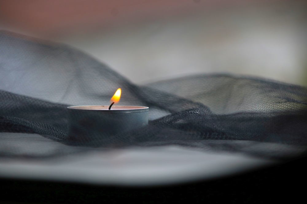 brennende Kerze auf schwarzem Stoff
