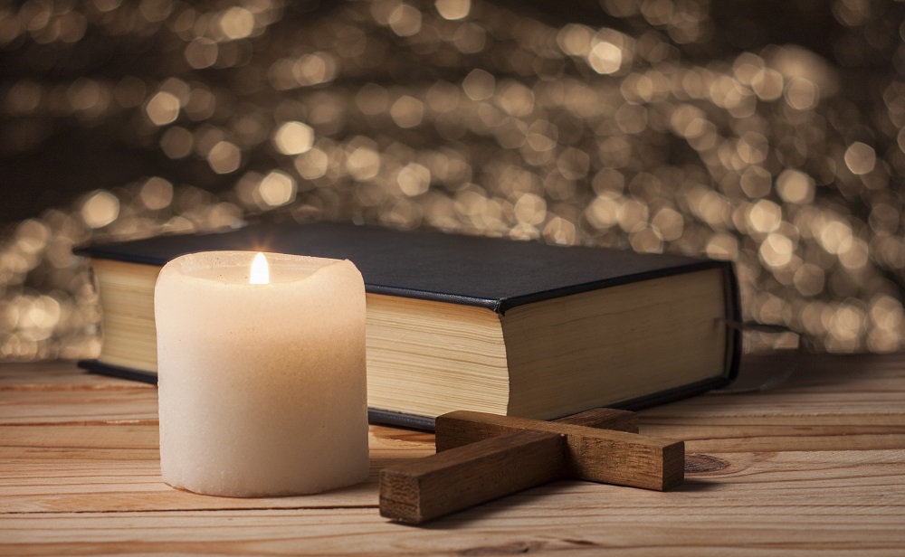 Kerze, altes Buch und Kreuz auf Tisch