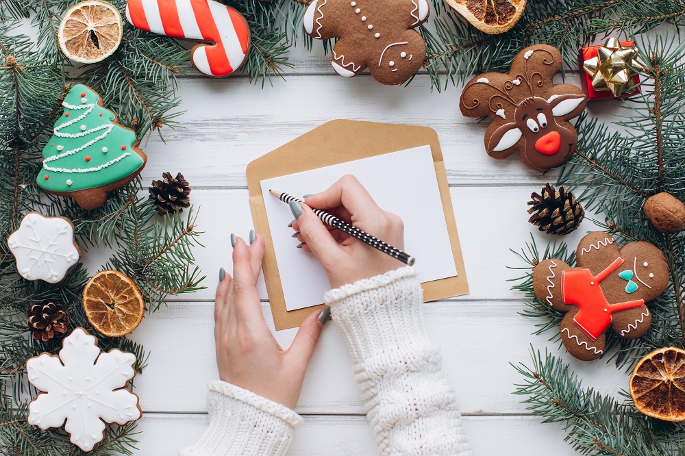Eine Frau schreibt Weihnachtsgrüße per Hand.